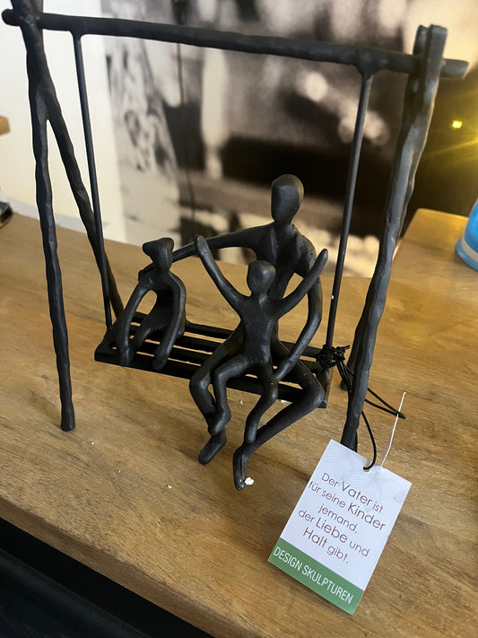 Skulptur, Vater mit Kindern auf Schaukel